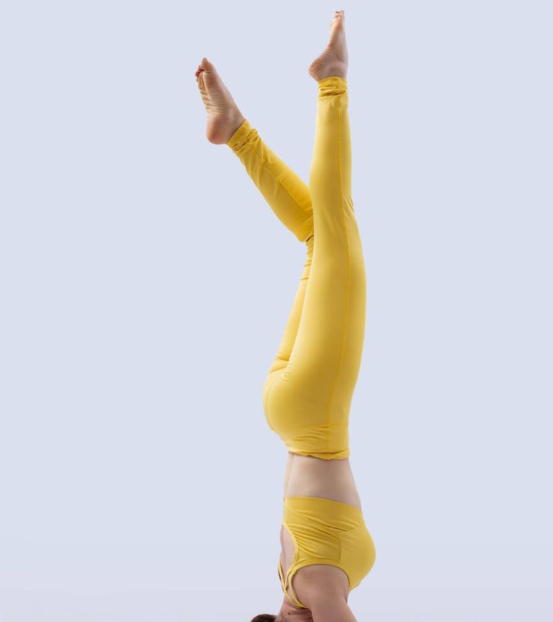 Woman performing a stability yoga pose in a dark studio setting.